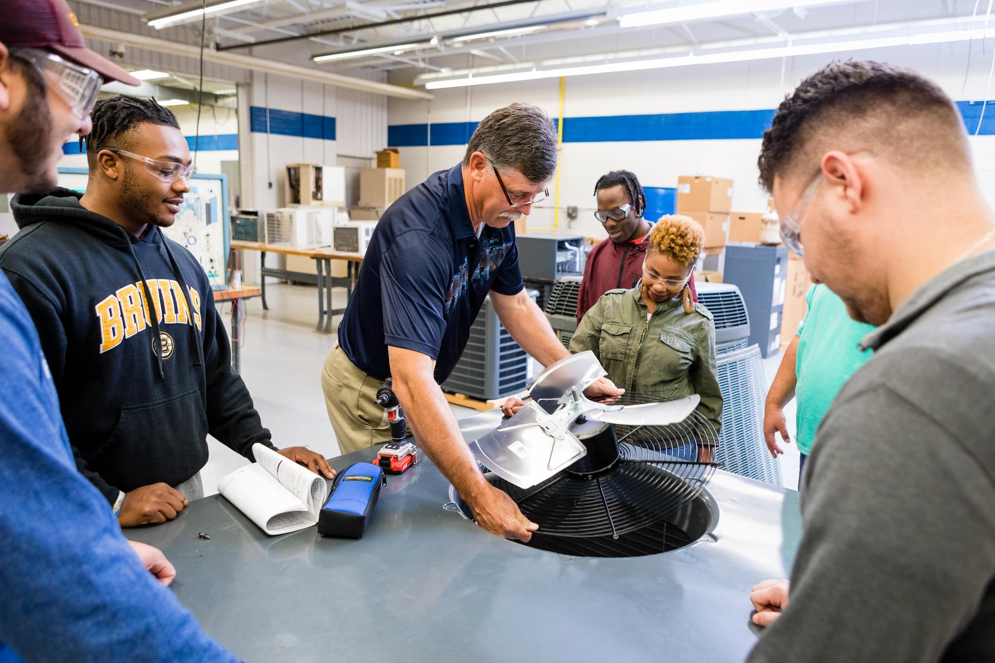 Teacher holds fan while student gather round