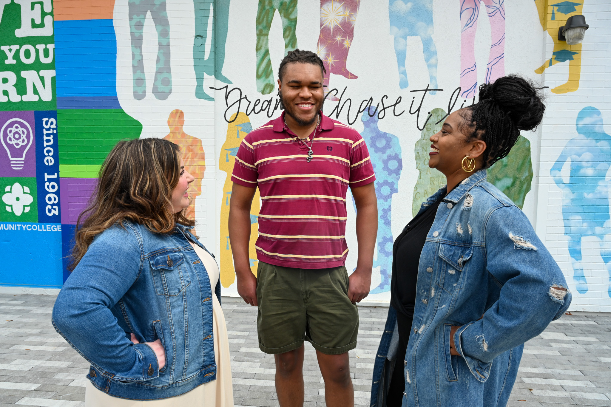 3 students stand together outside of SCC's mural.