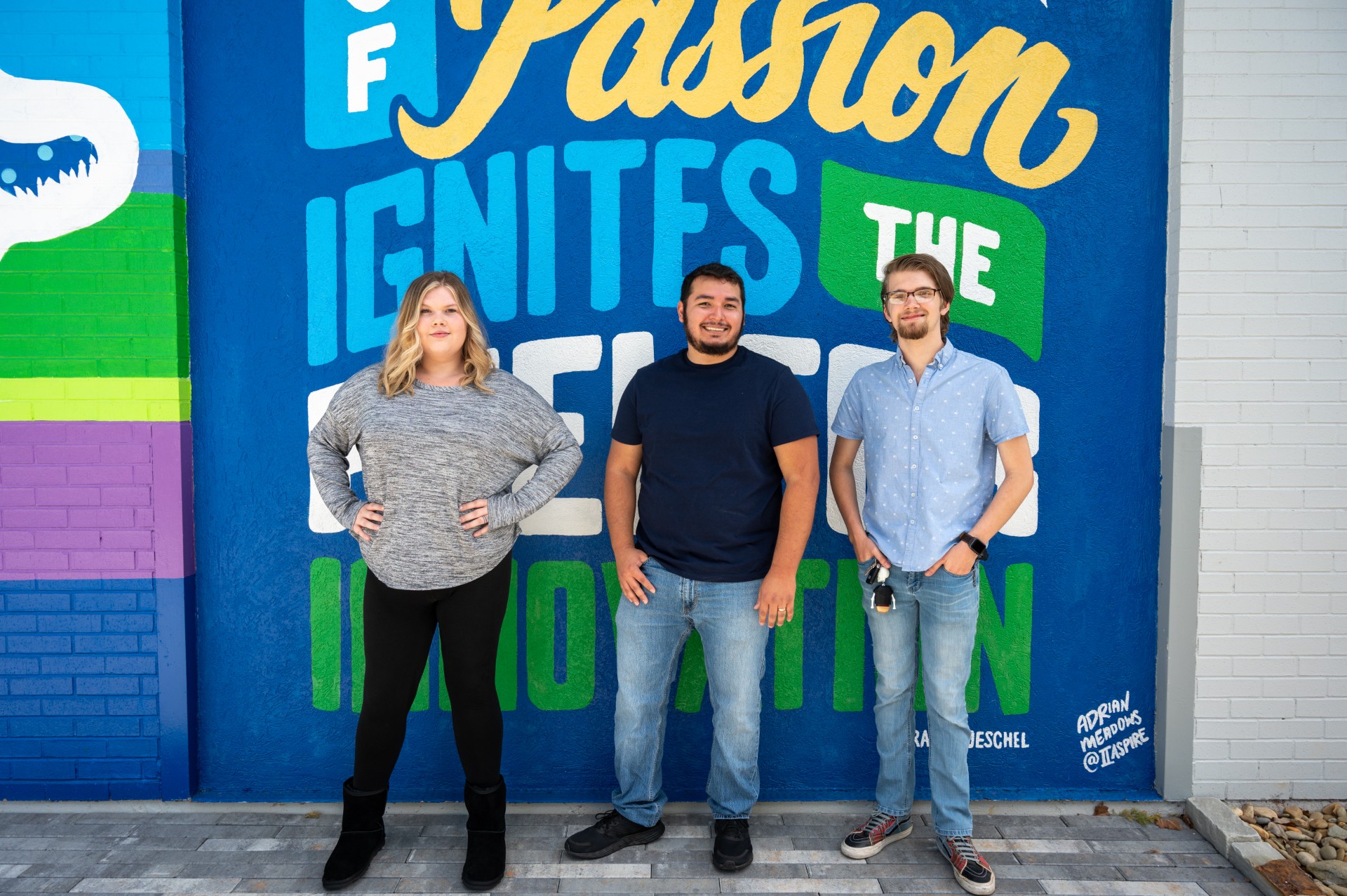 Three people standing in front of a wall